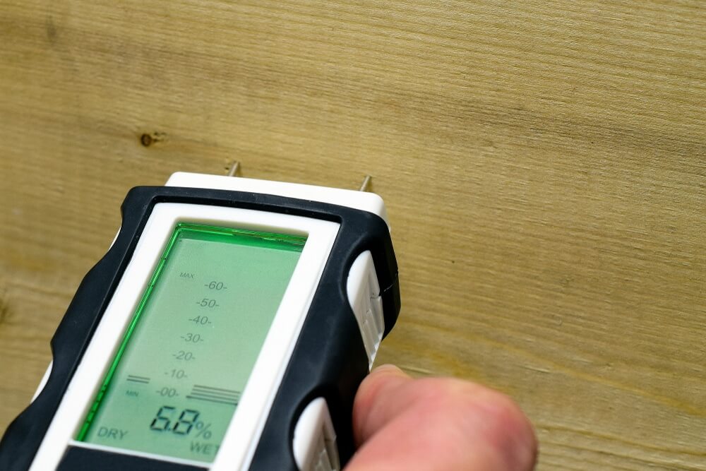 Wood Floor Waxing in Chelsea—moisture check on engineered oak hardwood floorboards with a pin meter showing 6.8% before finishing.