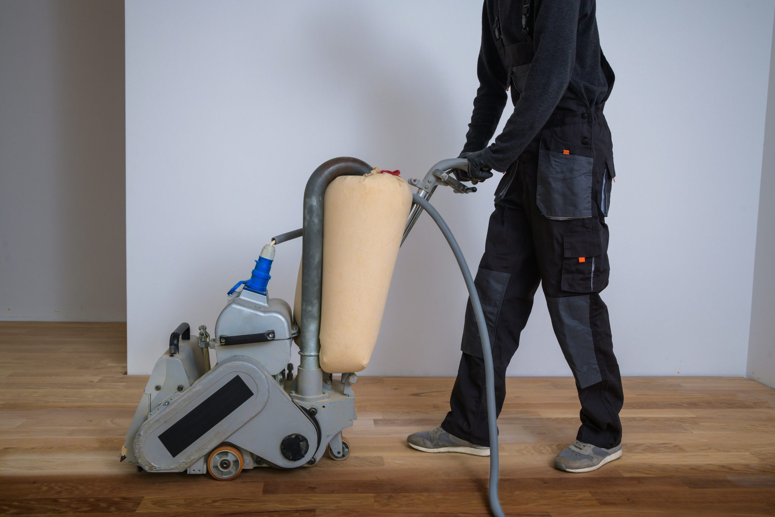 Wood Floor Waxing in Chelsea – professional sanding of European oak hardwood floor using a belt sander, preparing the boards for waxing and buffing.