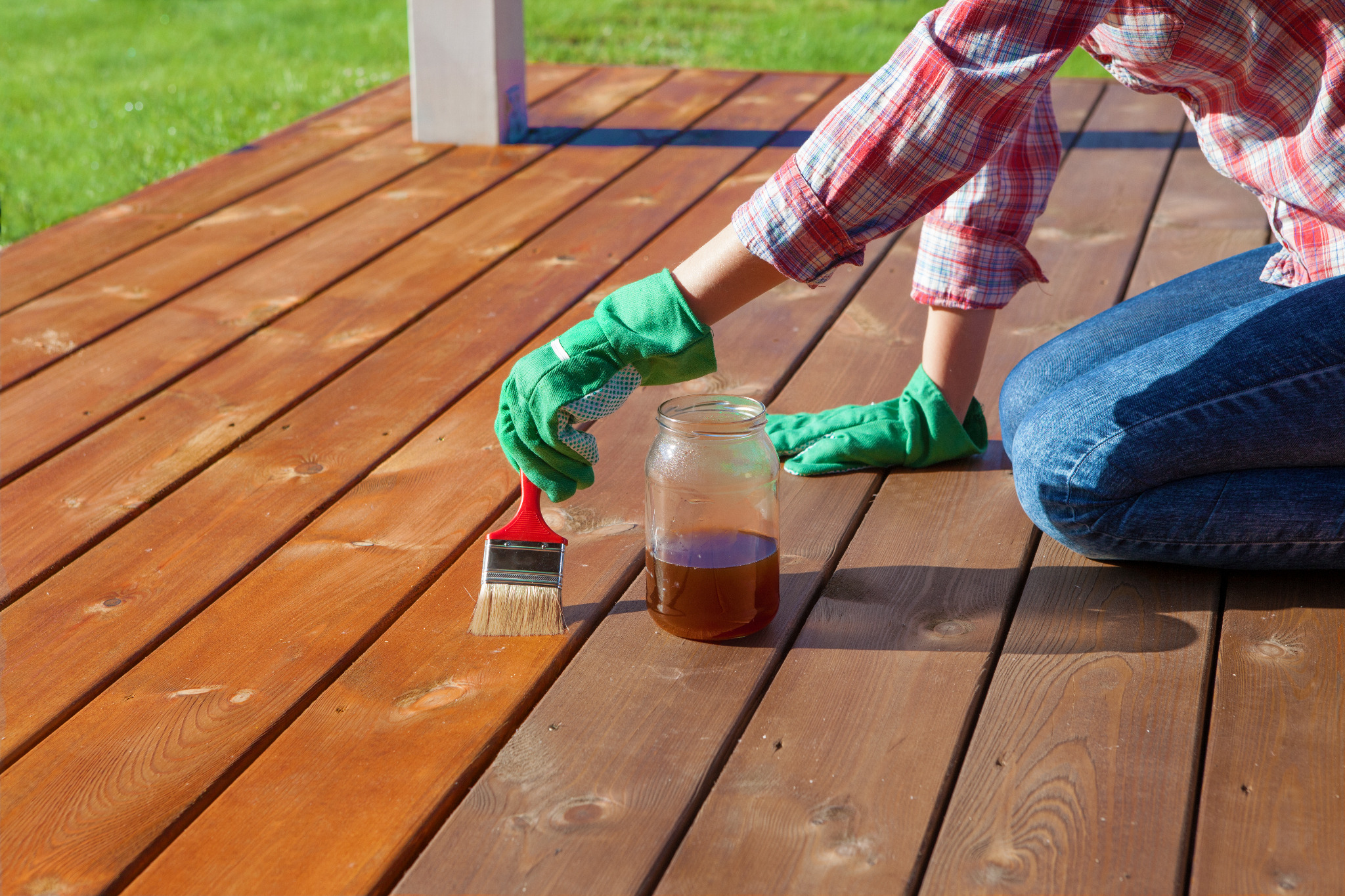 Applying protective oil after Deck Sanding in Chelsea on a softwood timber garden decking floor, showing rich, warm wooden boards.