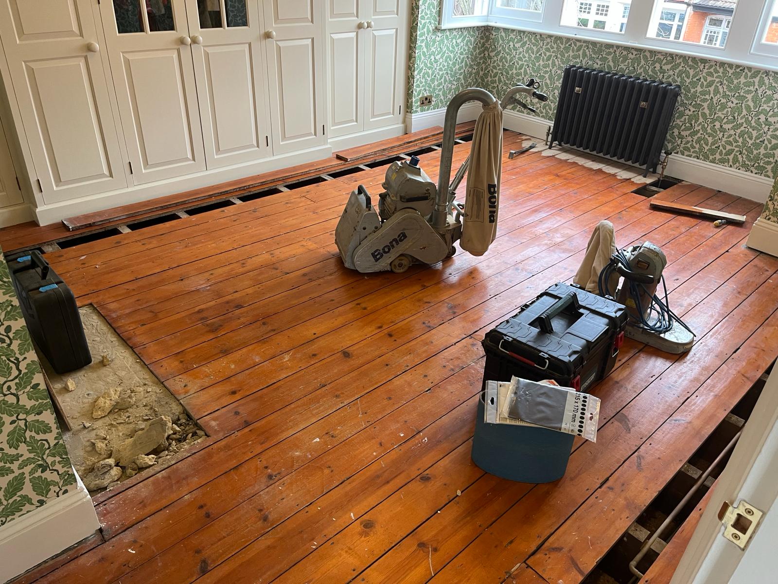 Wood Floor Sanding in Chelsea on original solid pine floorboards in a bedroom, with sanding machines and tools set up before restoration.