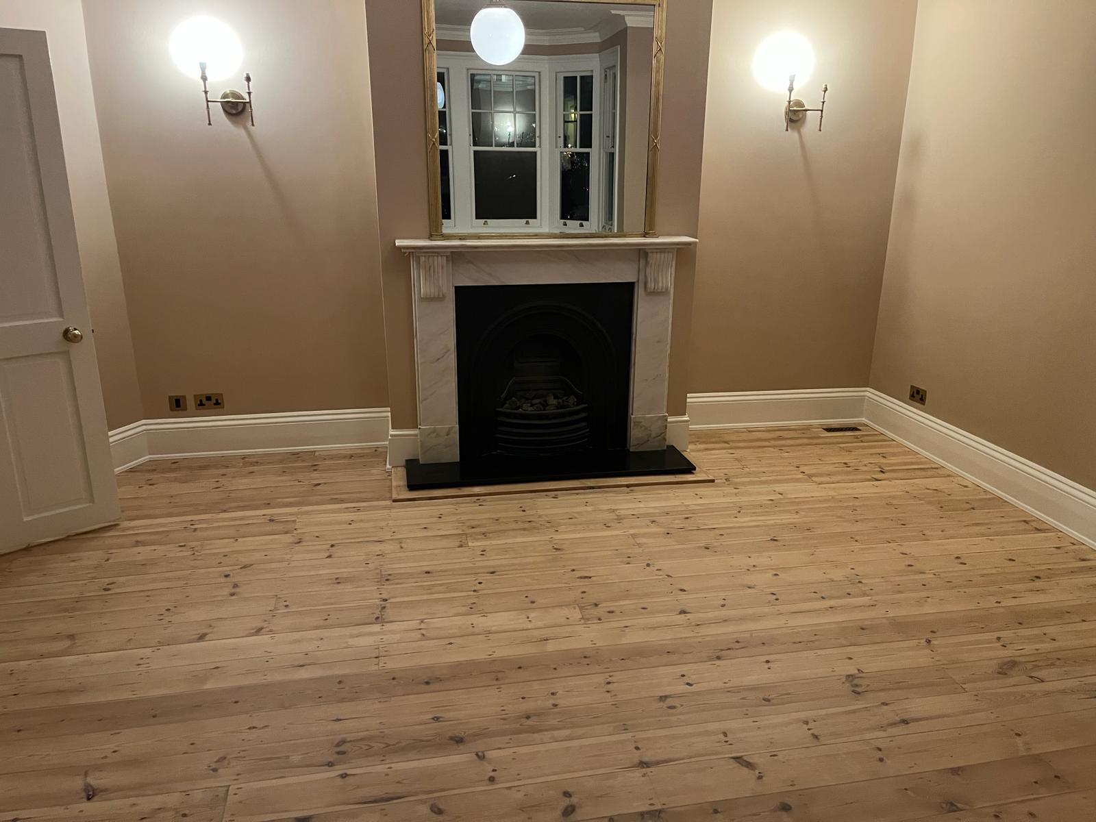 Wood Floor Sanding in Chelsea on restored solid pine floorboards in an elegant living room with feature fireplace.
